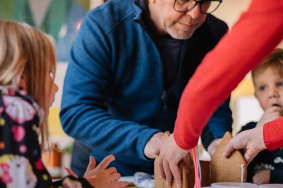 kids with grandparents making a gingerbread house