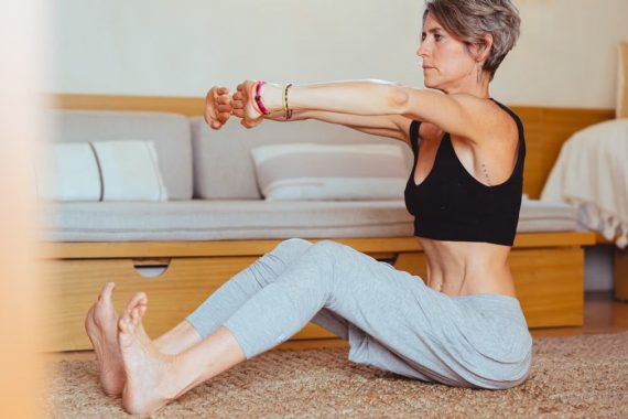 Elderly woman in a yoga pose indoors, embracing healthy lifestyle and wellness.
